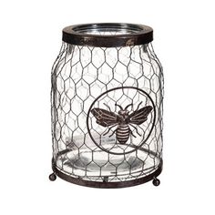 a glass jar with a bee on the inside and a wire mesh cover around it