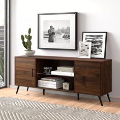 a sideboard with some books and pictures on it next to a potted plant