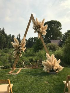 an outdoor ceremony setup with tall pamodia flowers and feathers on the back of chairs