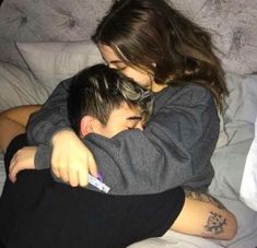 a woman hugging a man on top of a bed