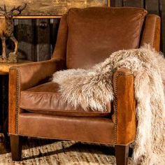 a brown leather chair sitting next to a wooden table with a deer head on it