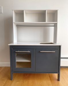 a gray and white toy kitchen with cupboards