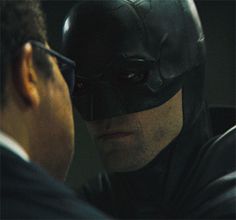 a man in a batman mask looking into another man's face