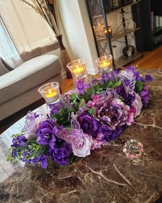 a table with candles and flowers on it in front of a couch, coffee table