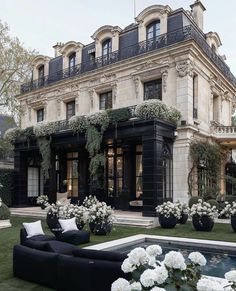 a black couch sitting on top of a lush green field next to a swimming pool