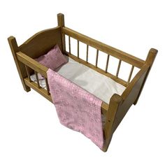 a small wooden crib with a pink blanket on the bottom and white sheets underneath