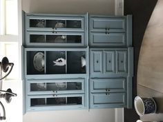 the kitchen cabinets are painted blue and have glass inserts on each side that hold dishes