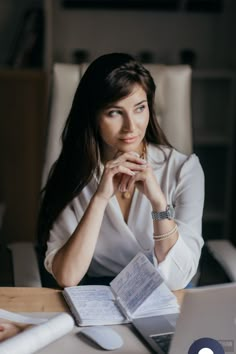 a woman sitting at a desk with her hands on her chin