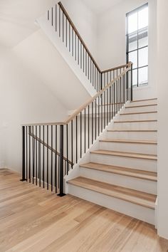 an empty room with white walls and wooden floors is pictured in this image, there are two sets of stairs leading up to the second floor