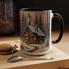 a coffee mug with a snowy cabin scene on it and a spoon next to it