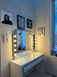 a white vanity with lights on it in front of a window and a large mirror