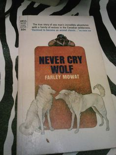 the book never cry wolf by farley mowwat is on top of a zebra print tablecloth