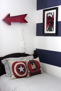 a bedroom with captain america pillows and an arrow decoration on the wall above the bed