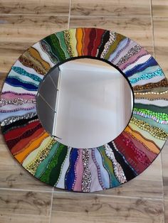 a multicolored mirror sitting on top of a tiled floor