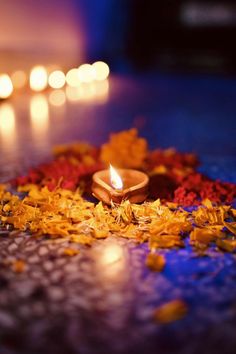 a lit candle surrounded by flowers and petals