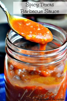 a spoon full of bbq sauce on top of a jar with the words spicy texas barbecue sauce