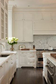 a large kitchen with white cabinets and marble counter tops, along with an oven and dishwasher