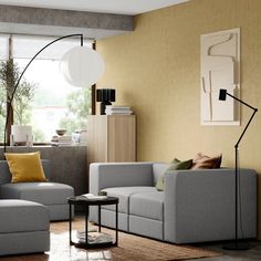 a living room with two couches and a lamp in the corner on the wall