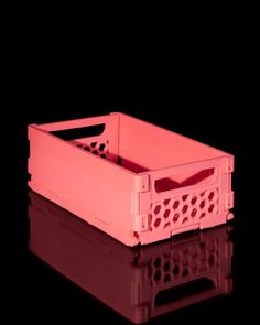 a pink plastic crate sitting on top of a black surface