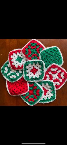 several crocheted coasters are arranged on a wooden table with a black background