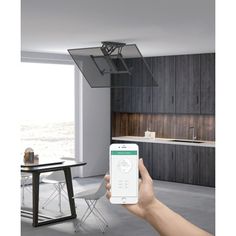 a person holding up a smart phone in front of a kitchen with dark wood cabinets