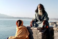 an old man sitting next to a woman in front of the ocean on a sunny day