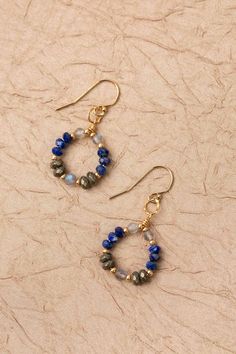 From the Blue Moon collection, these earrings come is a fun hoop design with shades of blue and elements of gold.. Gold Filled (nickel and lead-safe) Lapis, Pyrite, Labradorite 1.5", with gold filled ear wires We hand select our natural materials, thus there may be slight variations in color and/or size that will not detract from the overall aesthetic Our unique handcrafted designer jewelry for women is made in America, each design created individually in our personal design studio in Floyd VA U Gemstone Beaded Earrings, Blue 14k Gold Filled Hoop Jewelry, Blue Wire Wrapped Hoop Earrings, Blue Wire Wrapped Round Hoop Earrings, Hypoallergenic Blue Circular Jewelry, Blue Hoop Brass Jewelry, Blue Brass Hoop Jewelry, Blue Natural Stone Hoop Jewelry, Blue Hoop Jewelry With Natural Stones