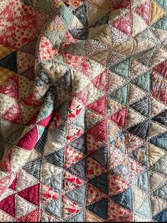 an old quilt that has been made into a blanket with many different colors and patterns