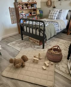 a teddy bear is sitting on the floor in front of a bed and rugs