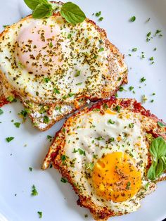 two pieces of toast with an egg on top and basil sprinkled on the side