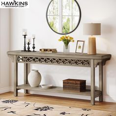 a console table with vases and candles on it in front of a round window