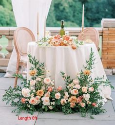 the table is set with flowers and candles for an outdoor wedding reception in front of a gazebo