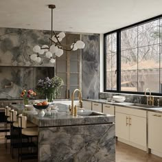 a kitchen with marble counter tops and an island in front of a large window that looks out onto the woods