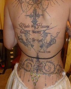 the back of a woman's body with tattoos and words on her lower back