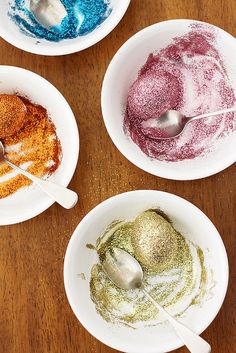 four bowls filled with different colored food on top of a wooden table