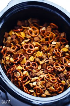 a crock pot filled with cereal and pretzels to make a snack or appetizer