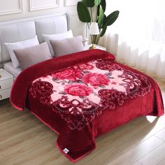 a bed covered in a red blanket with flowers on it