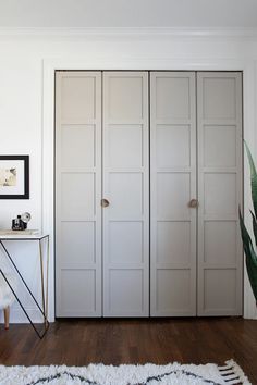 a bedroom with white closet doors and wooden flooring next to a rug on the floor