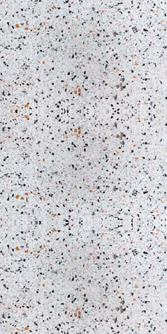 a white surface with black, orange and grey speckles on it's edges