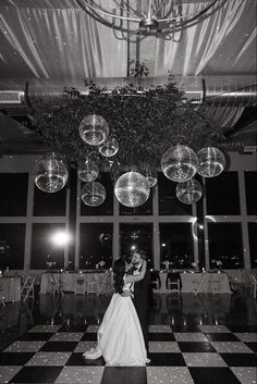 a bride and groom dance on the dance floor in front of large chandeliers