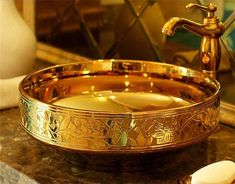 a golden bowl sitting on top of a counter next to a toothbrush and soap dispenser