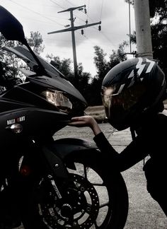 a person wearing a helmet leaning on a motorcycle with their hand on the handlebars