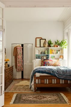 a bedroom with a bed, dresser and bookcase in the corner next to a window