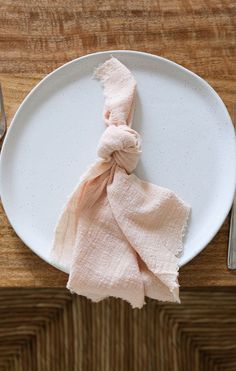 a white plate with a pink napkin on top of it next to a fork and knife