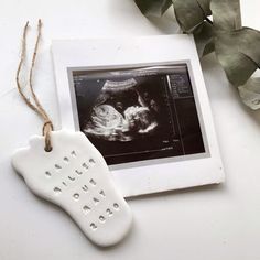 an ornament hanging from a string next to a photo with a foot print on it