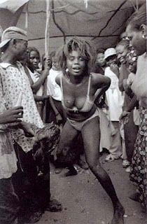 a black and white photo of a woman in a bathing suit dancing on the street