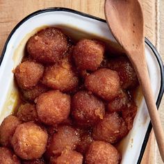 a bowl filled with fried food next to a wooden spoon