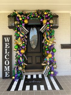 a welcome sign and wreath on the front door of a house decorated for mardi gras