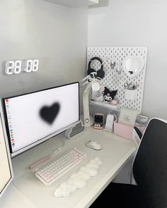 a white desk with a computer monitor and keyboard on it in front of a clock