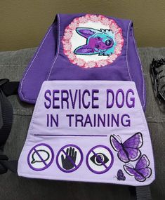 the service dog in training vest is purple and has an image of a butterfly on it